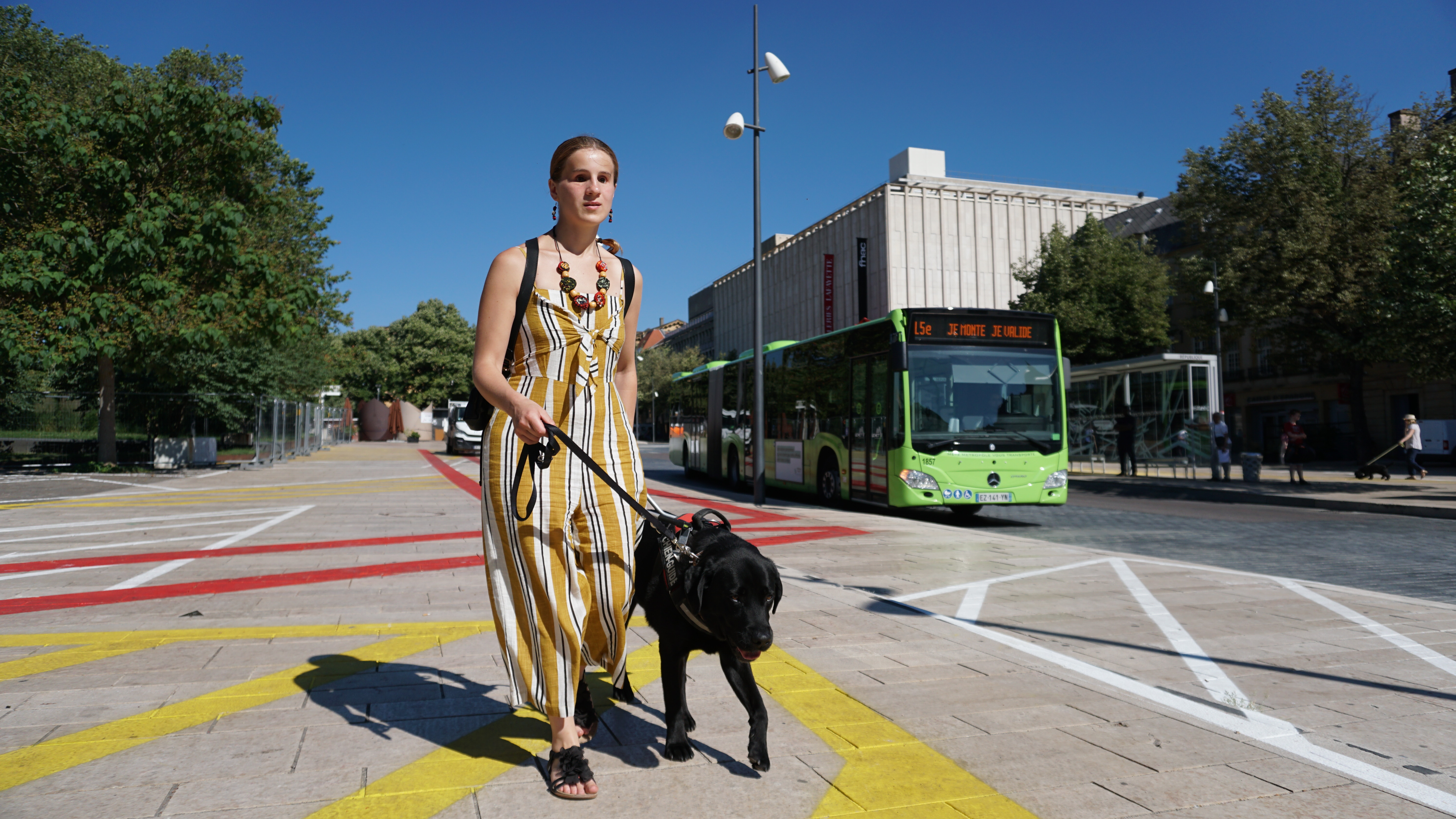 Femme se promenant avec chien guide noir au centre-ville